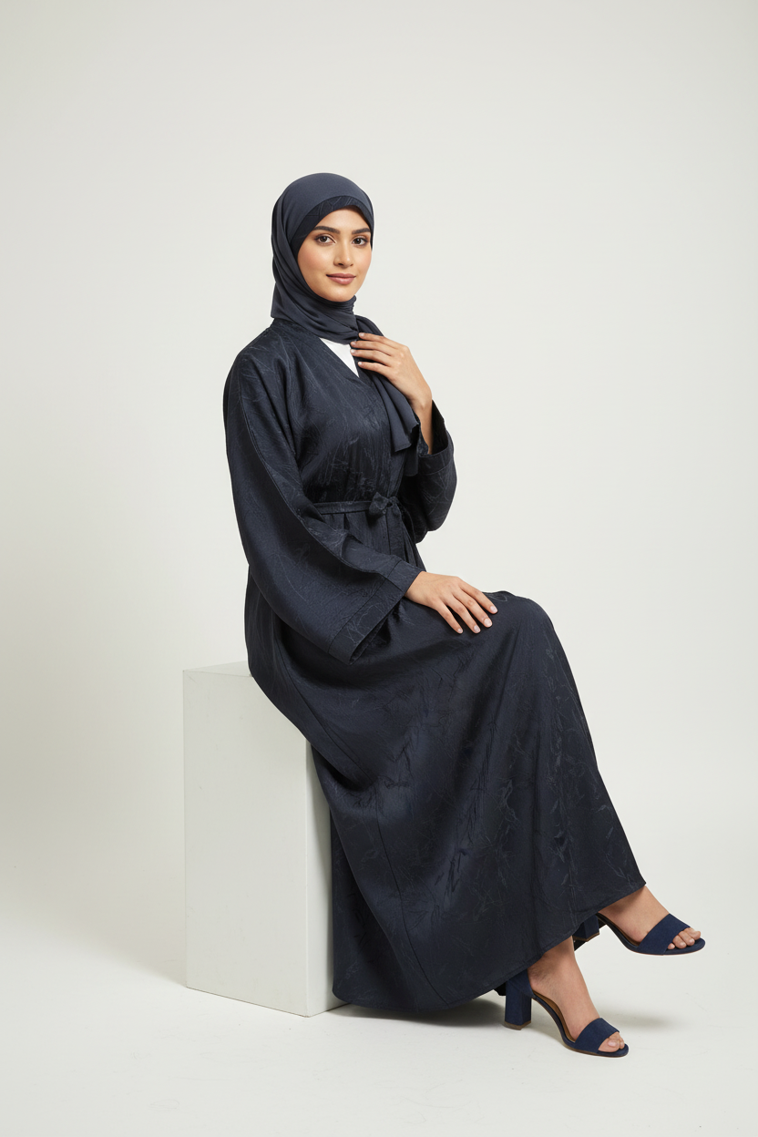 Woman wearing a dark blue abaya sitting on a white 