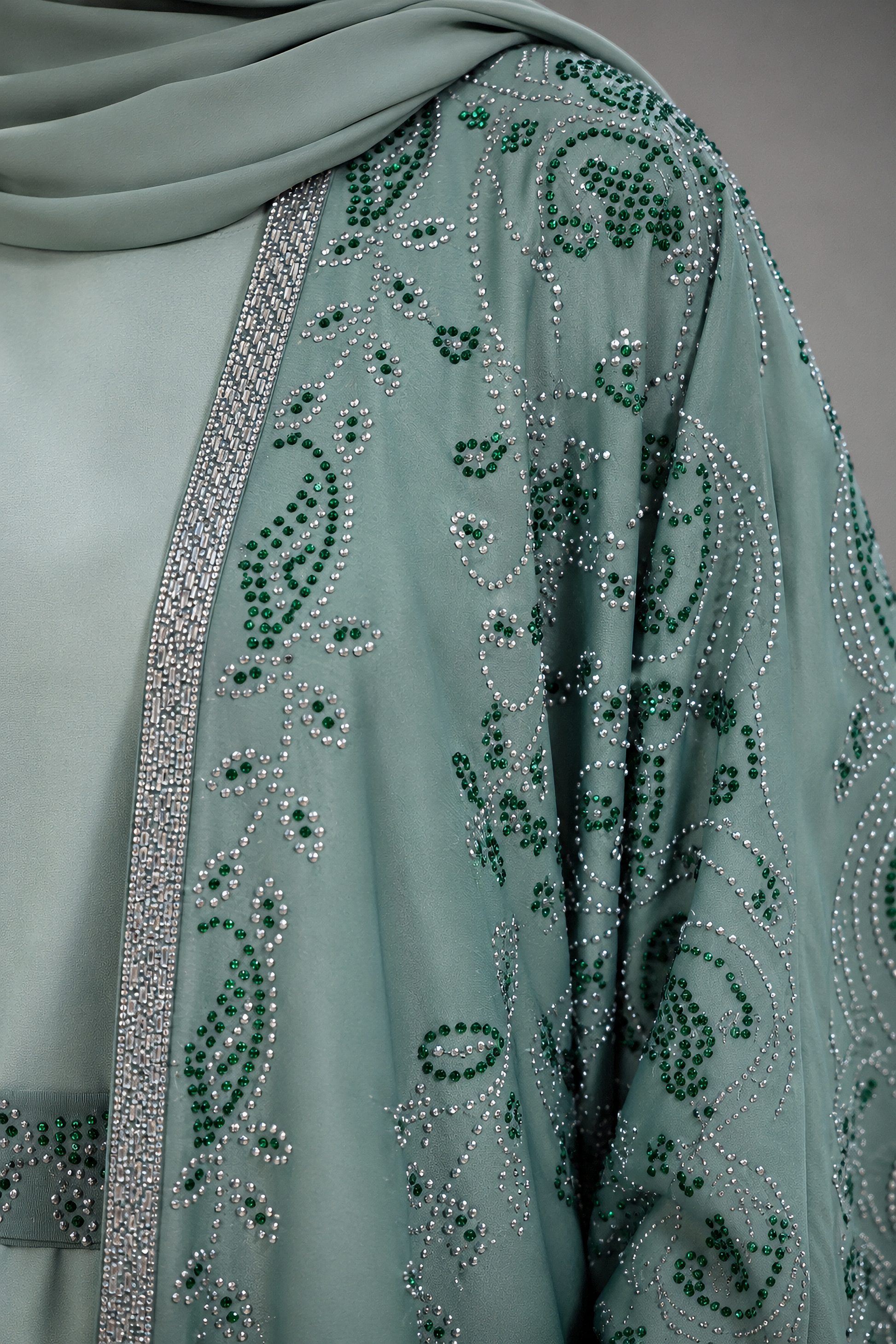 A close-up of a sage green traditional garment with intricate silver and green beaded paisley embroidery and a matching draped dupatta.